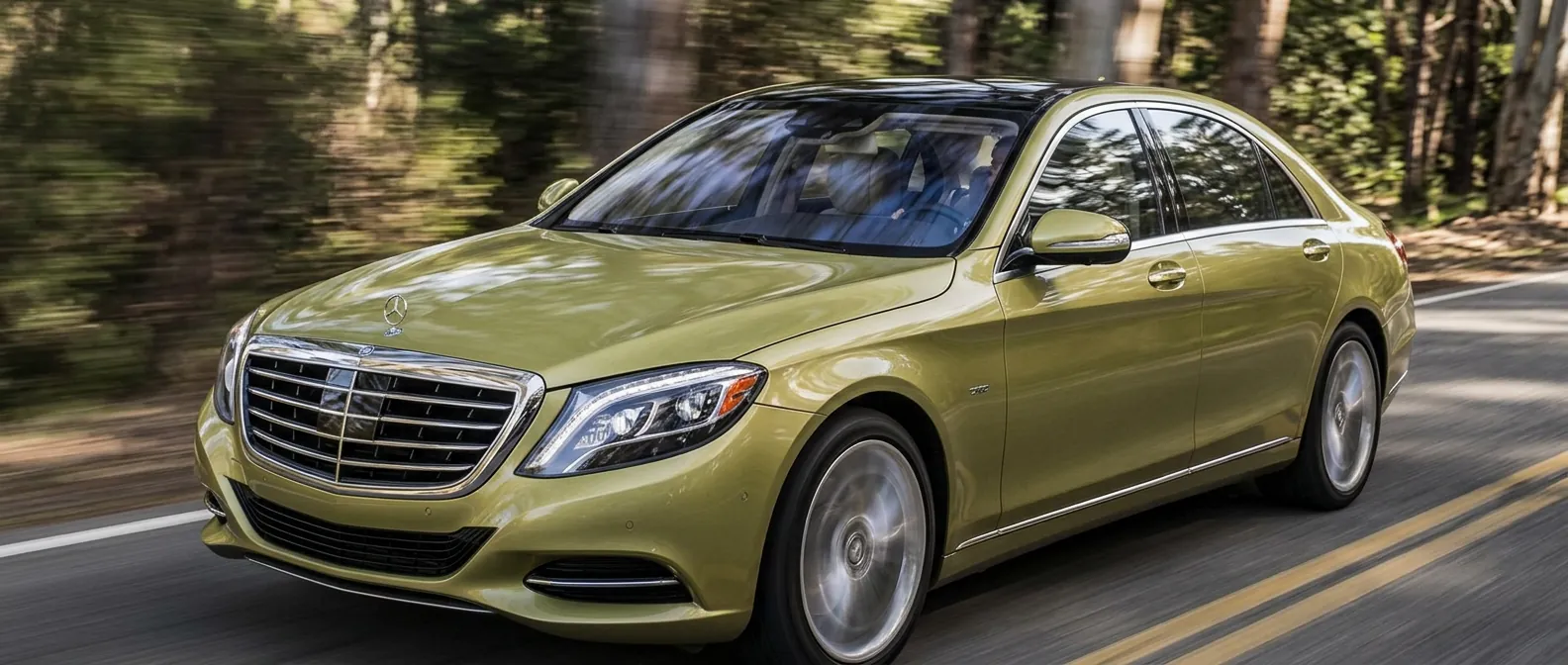 Chauffeur-driven luxury saloon travelling at speed on a tree-lined road